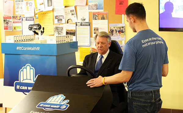 AT&T Employee Zack Smith (right) tells Sen. John Wozniak (left) how the texting and driving simulator works.