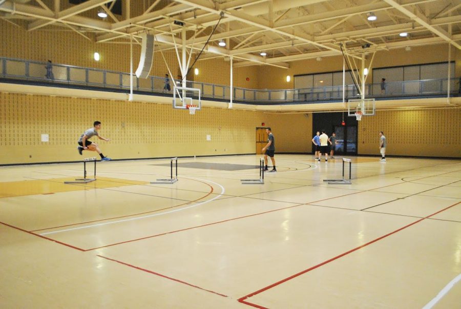 Freshman+John+Paronish+%28left%29+leaps+over+a+hurdle+during+a+track+and+field+team+practice+at+the+Wellness+Center+Jan+23.